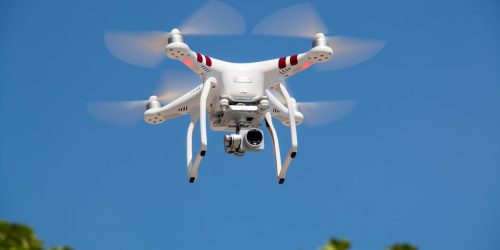 A white drone flying with camera against a clear blue sky in La Libertad.